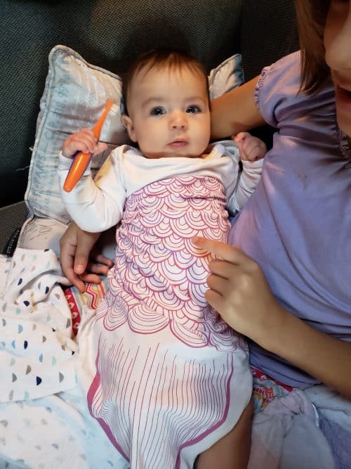 Baby holding toothbrush looking at camera. 